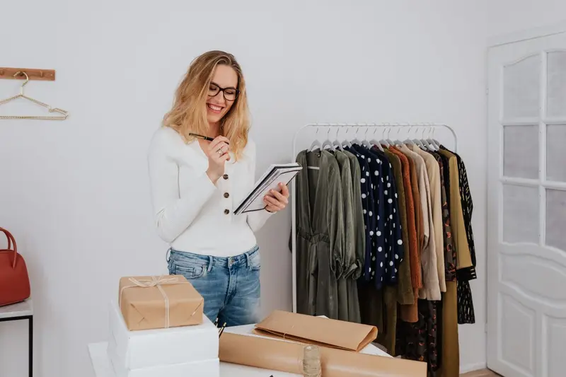 Dueña de una boutique tomando notas junto a su ropa, cliente típica de una web con SEO local
