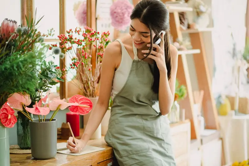 Dueña de una floristería atendiendo a una clienta, a quien le pedirá una reseña en Google